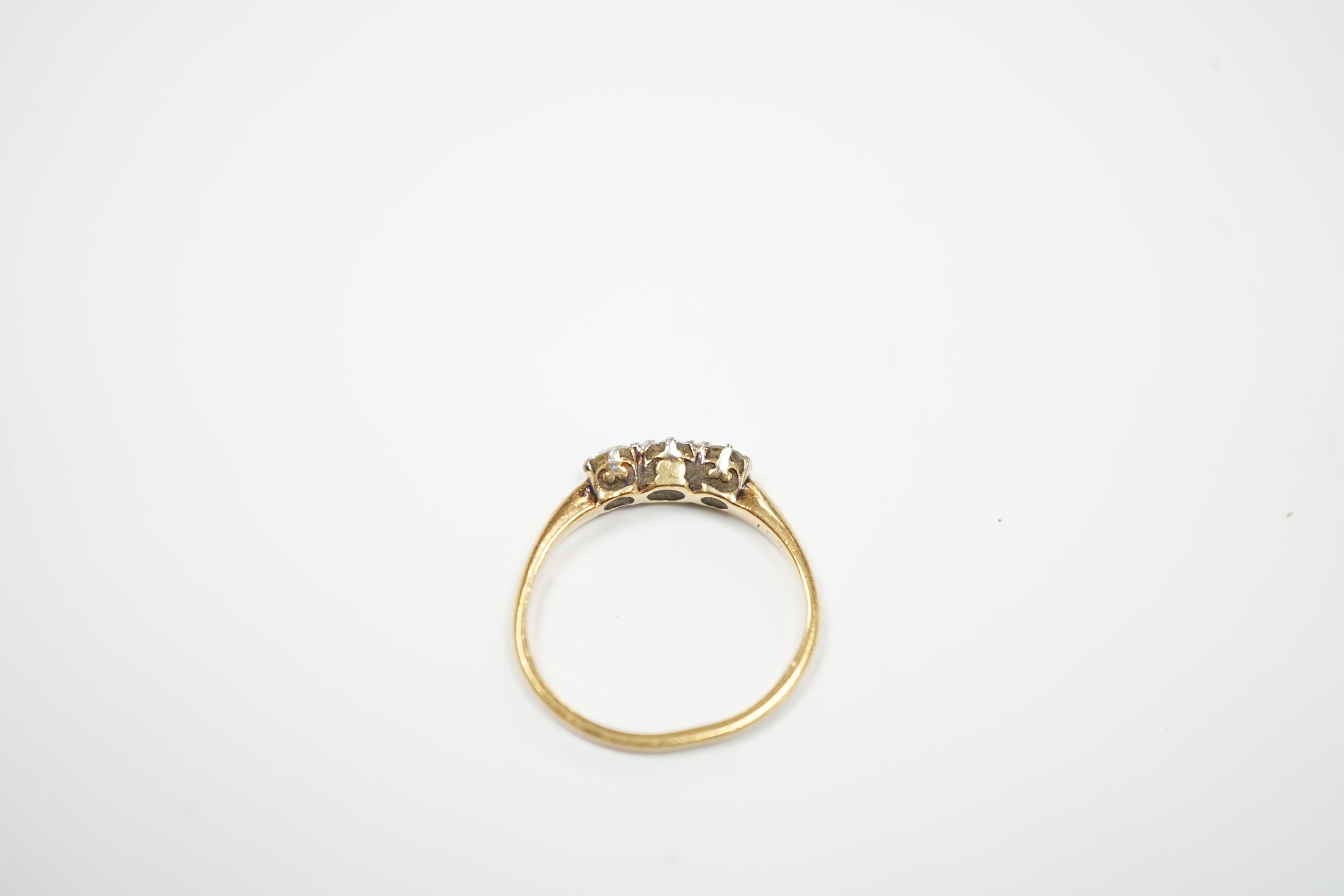 A yellow metal and three stone diamond set ring, size M, gross weight 2.3 grams.